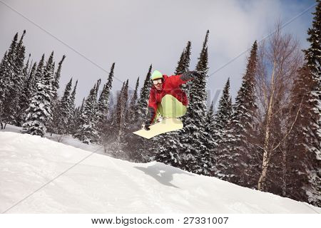 Snowboardista skoky vzduchem s tmavě modrou oblohou v pozadí
