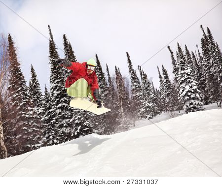 Snowboardista skoky vzduchem s tmavě modrou oblohou v pozadí