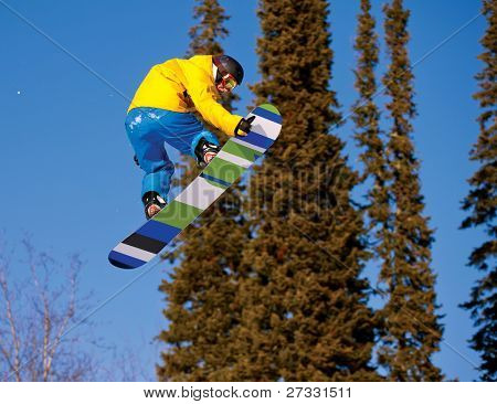Snowboardista skoky vzduchem s tmavě modrou oblohou v pozadí