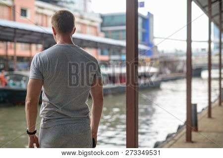 Rear View Of Young Tourist Man Waiting For The Boat Taxi At The Local Pier In Bangkok