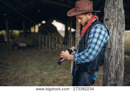 Brutal cowboy checks his revolver before gunfight