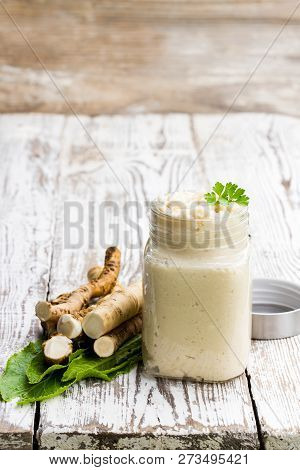 Spicy  Horseradish Sauce In Glass Jar On Wooden Table
