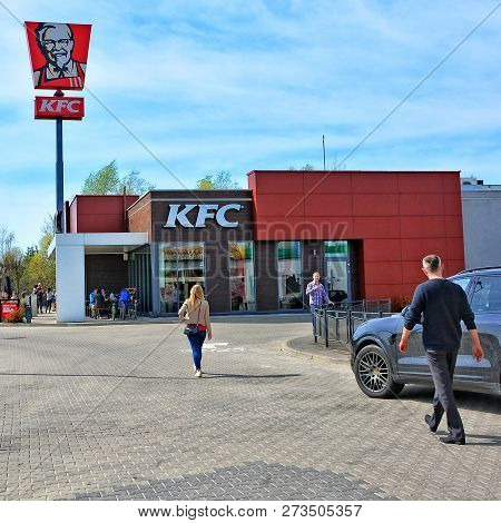 People Going To Kfc Restaurant. Fast Food Restaurant Chain On European Roads. Red Sign And Logo Of K