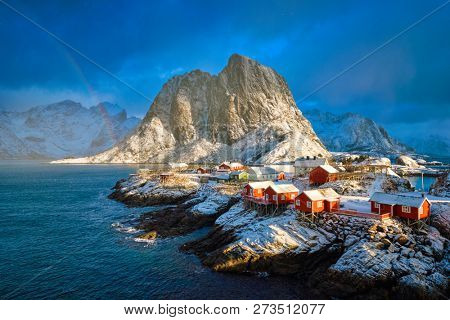 Hamnoy fishing village on Lofoten Islands, Norway with red rorbu houses. With falling snow in winter and rainbow