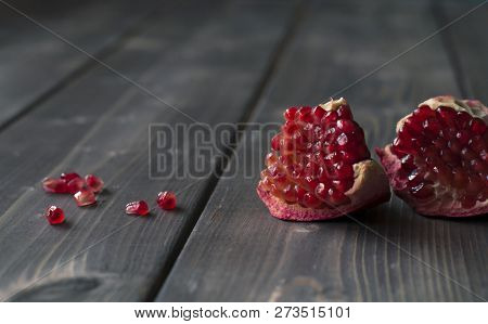 Red Pomegranate With Juicy Seeds On Wooden Kitchen Table