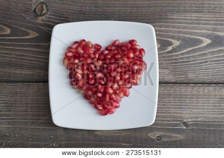 Red Pomegranate Seeds In Shape Of Heart In A Dish