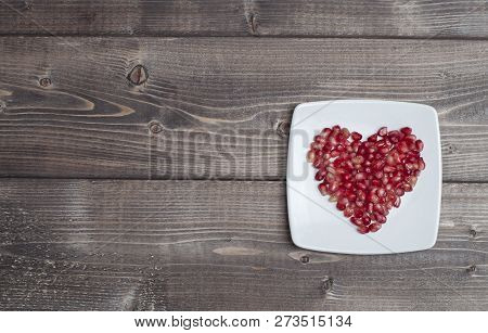 Red Pomegranate Seeds In Shape Of Heart In A Dish