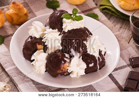 Chocolate Profiteroles With Whipped Cream On White Dish.
