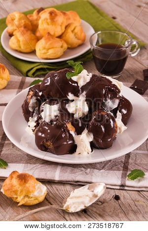 Chocolate Profiteroles With Whipped Cream On White Dish.