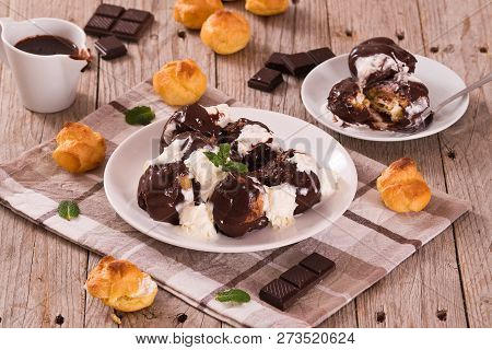 Chocolate Profiteroles With Whipped Cream On White Dish.