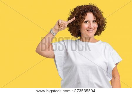 Beautiful middle ager senior woman wearing white t-shirt over isolated background Smiling pointing to head with one finger, great idea or thought, good memory