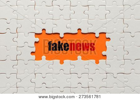 White Details Of Puzzle On Orange Background And Word Fake News