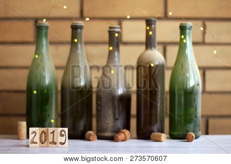 Wooden Plates With Numbers On A Blurred Background With Old Empty Bottles Of Wine / Need To Restock