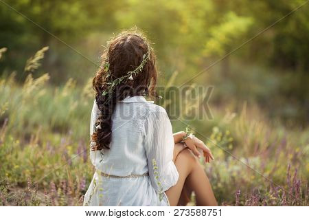Beautiful Young Woman Sitting On The Field In Green Grass. Outdoors. Enjoy Nature. Healthy Smiling G