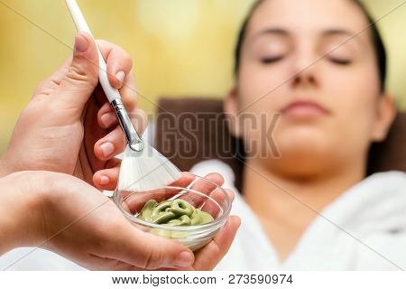 Close Up Of Hands Holding Bowl And Brush With Purifying Seaweed Pealing In Spa. Out Of Focus Woman L