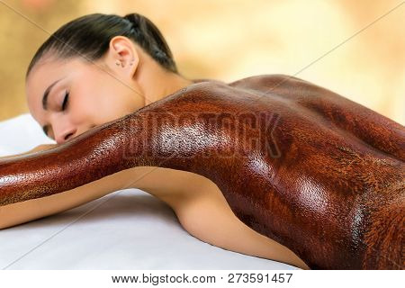 Close Up Detail Of Young Woman With Dark Chocolate Massage Wax Applied On Back. Girl Laying With Eye