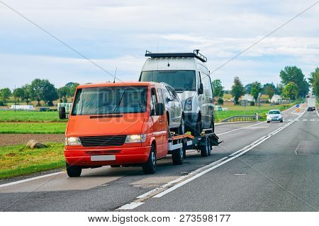 Car Carrying Trailer With Mini Vans On The Asphalt Road Of Slovenia.