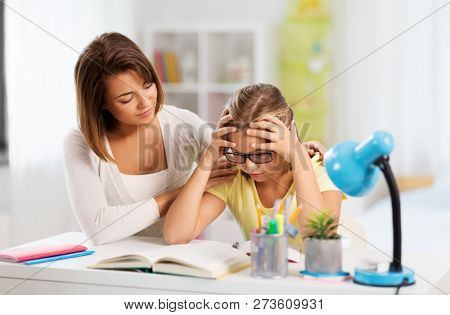education, family and learning concept - mother helping daughter with difficult homework task at home