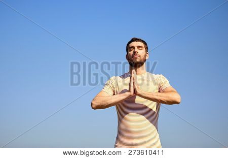 meditation, spirituality and mindfulness concept - man meditating outdoors over sky
