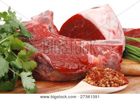 çiğ et: taze et domuz eti büyük göğüs ve fileto üzerinde beyaz izole ahşap üzerine sarımsak ve yeşil şeylerle