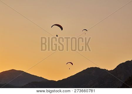 Paraglider Silhouette Flying Over Misty Mountain Valley In Beautiful Warm Sunset Colors - Sport, Act