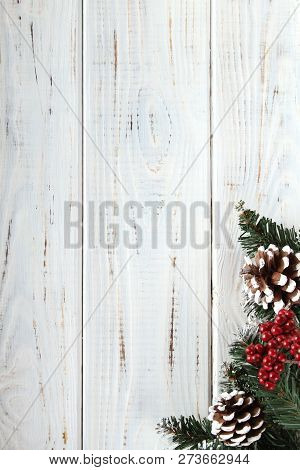Spruce Branches, Cones And Red Berries On A White Wooden Background. Background For Christmas And Ne