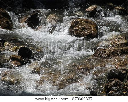 Water Flowing And Splashing Over Rocks In A Mountain River Stream