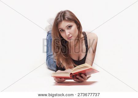 Young Attractive Caucasian Woman Lying On The Floor Legs Up, Book With Red Cover In The Hands, Sligh