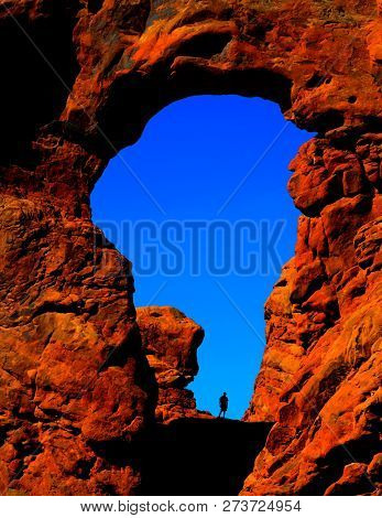 Silhouette of hiker in arch canyon rock formations