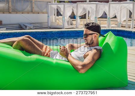 Young Man Enjoying Leisure, Lying On The Air Sofa Lamzac, Near The Pool