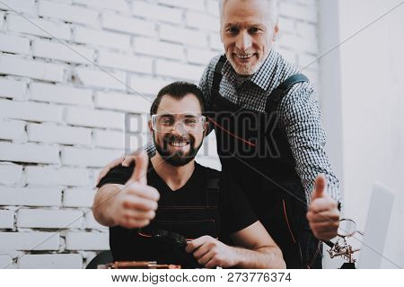 Two Exited Smiling Men In Uniform In Workshop. Repair Shop. Thumbs Up. Computer Hardware. Young And 