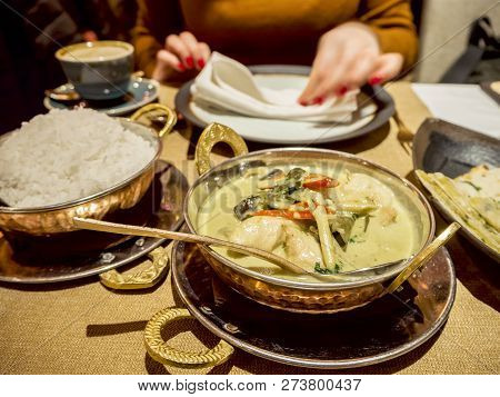 Woman At The Table And Indian Food. Oney Dipper,  Salt And Sugar Background. Asian Chicken In Coconu