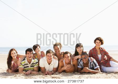 Grupp vänner sitter på stranden tillsammans