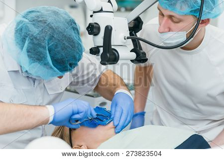 Doctor Used Microscope. Dentist Is Treating Patient In Modern Dental Office. Operation Is Carried Ou