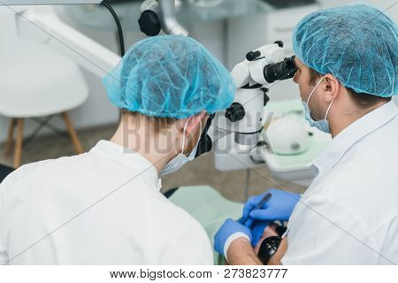 Doctor Used Microscope. Dentist Is Treating Patient In Modern Dental Office. Operation Is Carried Ou