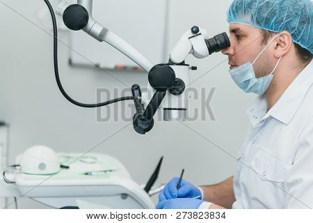 Doctor Used Microscope. Dentist Is Treating Patient In Modern Dental Office. Operation Is Carried Ou