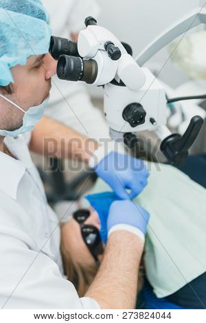 Doctor Used Microscope. Dentist Is Treating Patient In Modern Dental Office. Operation Is Carried Ou