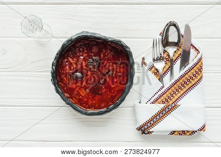 Top View Of Traditional Beetroot Soup With Cutlery And Glass Of Vodka On White Wooden Background