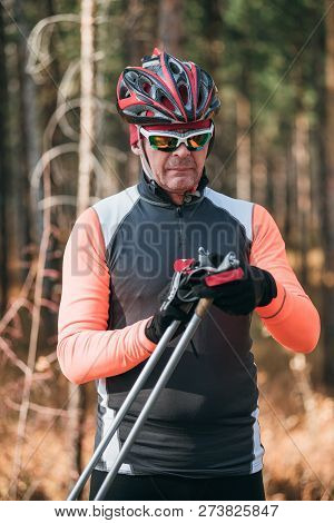 Training An Athlete On The Roller Skaters. Biathlon Ride On The Roller Skis With Ski Poles, In The H