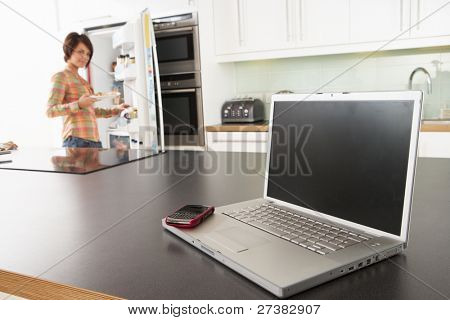 Junge Frau Befestigung Snack in Küche mit Laptop in moderne Küche