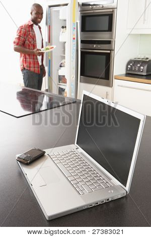 junger Mann Befestigung Snack in Küche mit Laptop in moderne Küche