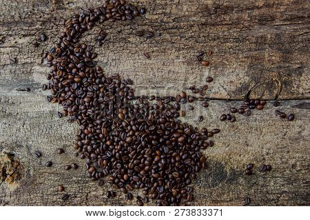 Coffee Beans On Wood Texture Background. Coffee Cup Full Of Coffee Beans.