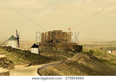 Road From Windmills To Castle Of Consuegra Between Yellow Clay Fields With Cloudy Horizon Outdoors. 