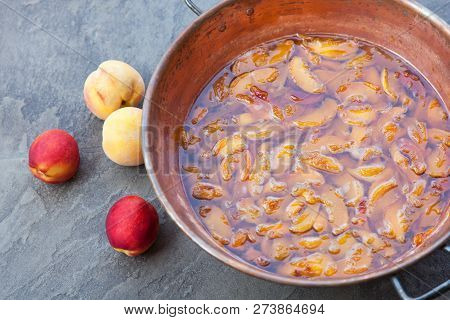 Fresh Bright Peaches And Nectarins Lay On The Stone Bricks, Close To The Copper Jar, Full Of Peach J