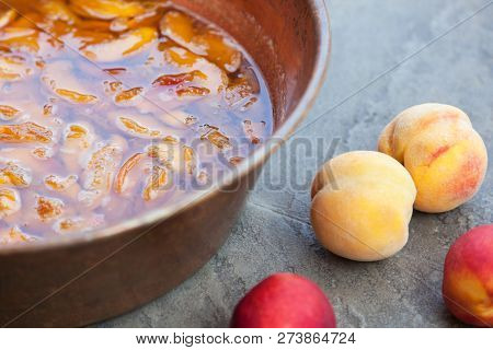 Fresh Bright Peaches And Nectarins Lay On The Kitchen Desk Close To The Copper Jar, Full Of Peach Ja