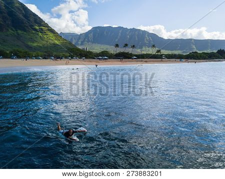 OAHU / USA - 12 NOVEMBER 2018: Aerial view of Makaha beach with the surfer paddling on the foreground.