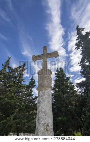 White Stone Cross Standing In Evergreen Forest