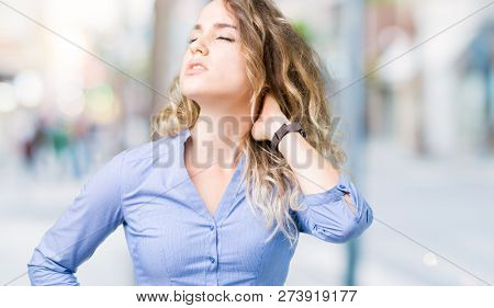 Beautiful young blonde business woman over isolated background Suffering of neck ache injury, touching neck with hand, muscular pain
