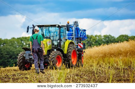 Vinnytsa, Ukraine - July 2017: A Young Handsome Farmer Standing On Farmland. Tractors Working In The