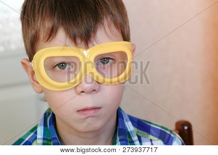 Seriosly Boy In Safety Yellow Goggles Sitting At The Table And Looking At Camera. Experiments On Che